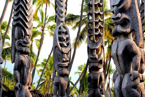 Carved wooden tiki statues tropical palms